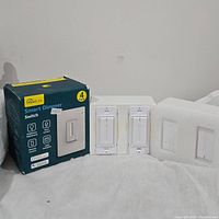 Photo showing four Treatlife Smart Dimmer Switches, two out of box and two still in packaging, along with the 4-pack box.