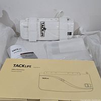 Photo showing the Tacklife thermal laminator, user manual, warranty card, lamination sheets, and original packaging box.