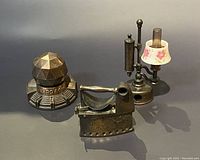 Three vintage metal pencil sharpeners with different unique designs shown together on a surface.