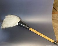 Full view of calligraphy brush showing long grooved bamboo handle and white bristles with black ferrule