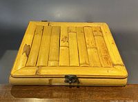 Closed bamboo tea box with clasp and vertical bamboo slats on lid.