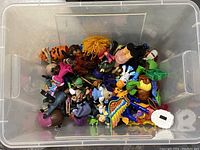 Top view of transparent plastic box filled with assorted small colorful toys and figurines.