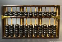 Front view of wooden Chinese abacus with brass crossbar and dark wood beads on vertical rods.