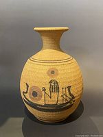Full view of the earthenware vessel showing its rounded shape, narrow neck, flared lip, and painted Egyptian boat and bird motif with circular decorations.