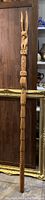 Full-length view of the carved cedar talking stick against wood panel background
