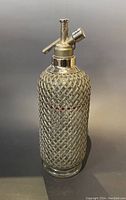 Full view of the seltzer bottle showing woven cover and siphon top