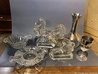 Full view of the lot with two clear glass horse figurines, silver metallic vase, clear glass bowl, clear glass ashtray, and etched goblet