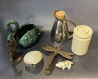 Photo of assorted decorative and household items showing various figurines, containers, and a metal pitcher.