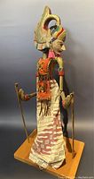 Full side view of the traditional Thai puppet standing on a base, showing wooden body, fabric clothing, and painted details
