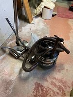 Image showing the complete Filter Queen metal canister vacuum with coiled hose and several metal wands attached, along with a metal floor nozzle.