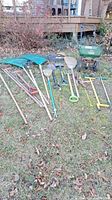 Full view of all garden tools arranged on grass showing shovels, rakes, hoe, pitchfork, clippers, and spreader