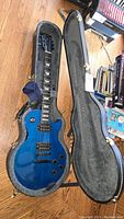Full view of blue Gibson Les Paul Model guitar inside open hard shell case