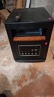 Front and side view of the black infrared heater with wood-tone trim and digital control panel, showing overall condition and design.