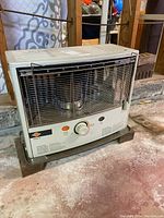 Front angle view of white Kero-Sun kerosene heater showing control knob, safety grill, and glass burner area.