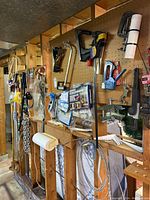Wall-mounted pegboard with various home repair tools hanging, including clamps, staplers, wire, and a funnel.