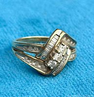 Front view of ring on blue cloth showing central round and baguette diamonds