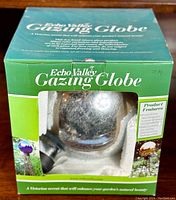 Echo Valley gazing globe visible through box window with foam inserts for protection. The globe has a reflective surface with speckled details.