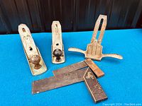 Full lot view showing two Stanley hand planes and two old carpenters squares on blue surface.