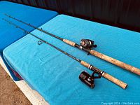 Two vintage Berkley fishing rods laid out showing cork handles and attached reels: an Abu Garcia Ambassadeur Mag II and a Daiwa spinning reel.