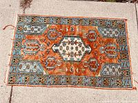 Full view of the rectangular Persian Oushak rug laid flat on a concrete surface showing overall color and pattern.