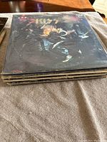 Stack of vinyl albums featuring KISS album on top with band members pictured in costume.