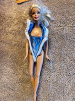 Full front photo of Barbie doll with blue and white sleeveless outfit and platinum blonde hair fanned out on carpet.