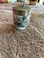 Front view of the porcelain container showing blue and white floral design and silver lid with loop handle