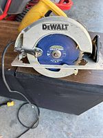 Front view of Dewalt electric circular saw showing blade labeled 'WIDIA TOUGH 40T' with metal blade guard and power cord attached.