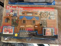 Front view of the Fisher Price Great Adventures All-in-One Western Fort in original packaging showing the toy and figurines inside plastic display.