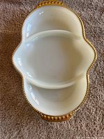 Top view of the white divided serving dish showing two compartments and gold beaded trim on handles.