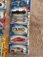 Photo showing five 2008 First Edition Hot Wheels cars in original packaging arranged vertically on carpet.