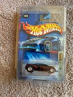 Front of unopened Hot Wheels Treasure Hunt Cadillac die-cast car packaging with branding and visible car model.