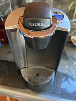 Front view of Keurig coffee machine showing drip tray and main coffee pod compartment with Keurig logo.