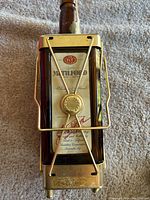 Front of whiskey decanter in brass frame, showing label with Mathlford branding and decorative brass medallion and crossbars.