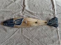 Top-down view of wooden fish-shaped towel holder laid flat, showing three metal hooks on its body.