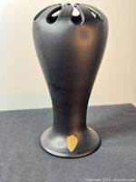 Full view of the black satin art deco vase showing flared top with rounded cutouts and slender body on black surface.