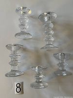 Top-down view of all five Iittala Festivo glass candlesticks showing variation in ring count and size.