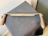 Full view of the antique keen cutter with metal blade and wood handles, placed on black fabric.