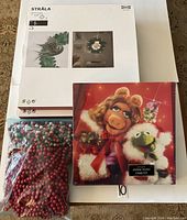 All items included in the lot displayed together: 2 IKEA Strala wreath boxes, vintage Miss Piggy puzzle, bag of cranberry garlands.