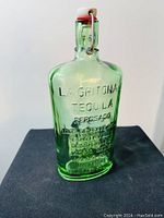 Front and side view of green glass La Gritona Tequila Reposado collectible bottle.
