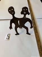 Front perspective view of the Murat Brierre metal sculpture showing two conjoined human figures with smiling faces and cutout eyes.