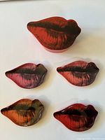 Five items shown: large lidded box and four lips shaped trays in multiple colors