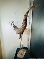 Full view of the metal heron garden sculpture showing its height and artistic metal feather design on the body, copper-brown rusted finish.