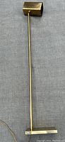 Full length photo of the brass floor lamp showing the long vertical rod and rectangular lamp head.