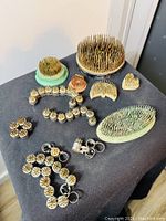 Complete view showing various vintage metal needle point flower frogs arranged on table with different shapes and sizes including rings and larger flat bases.