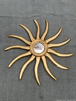 Front view of the vintage sun mirror on gray surface showing full design and convex glass.