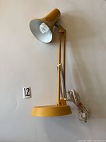 Full view of vintage yellow Luxo articulating desk lamp showing lamp, base, arm, and power cord.
