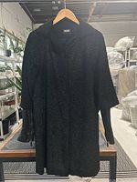 Front view of coat hanging on wooden hanger in warehouse