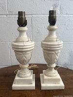 Front view of both marble lamps showing urn-shaped bodies and square bases