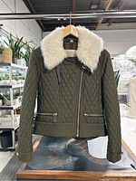 Full front view of olive green quilted jacket with shearling collar hanging on wooden hanger